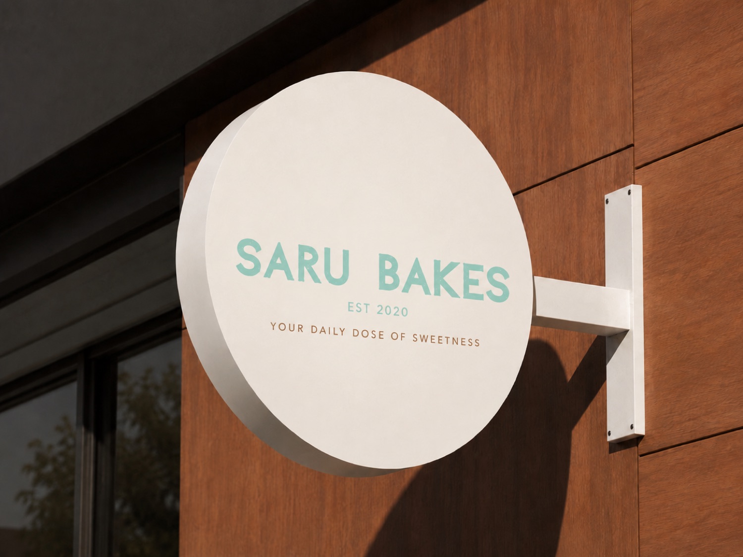 Saru Bakes round blade sign mounted on a wood storefront facade